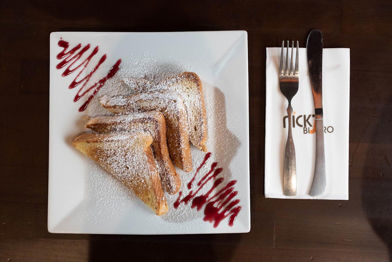 A plate of french toast with powdered sugar and jam